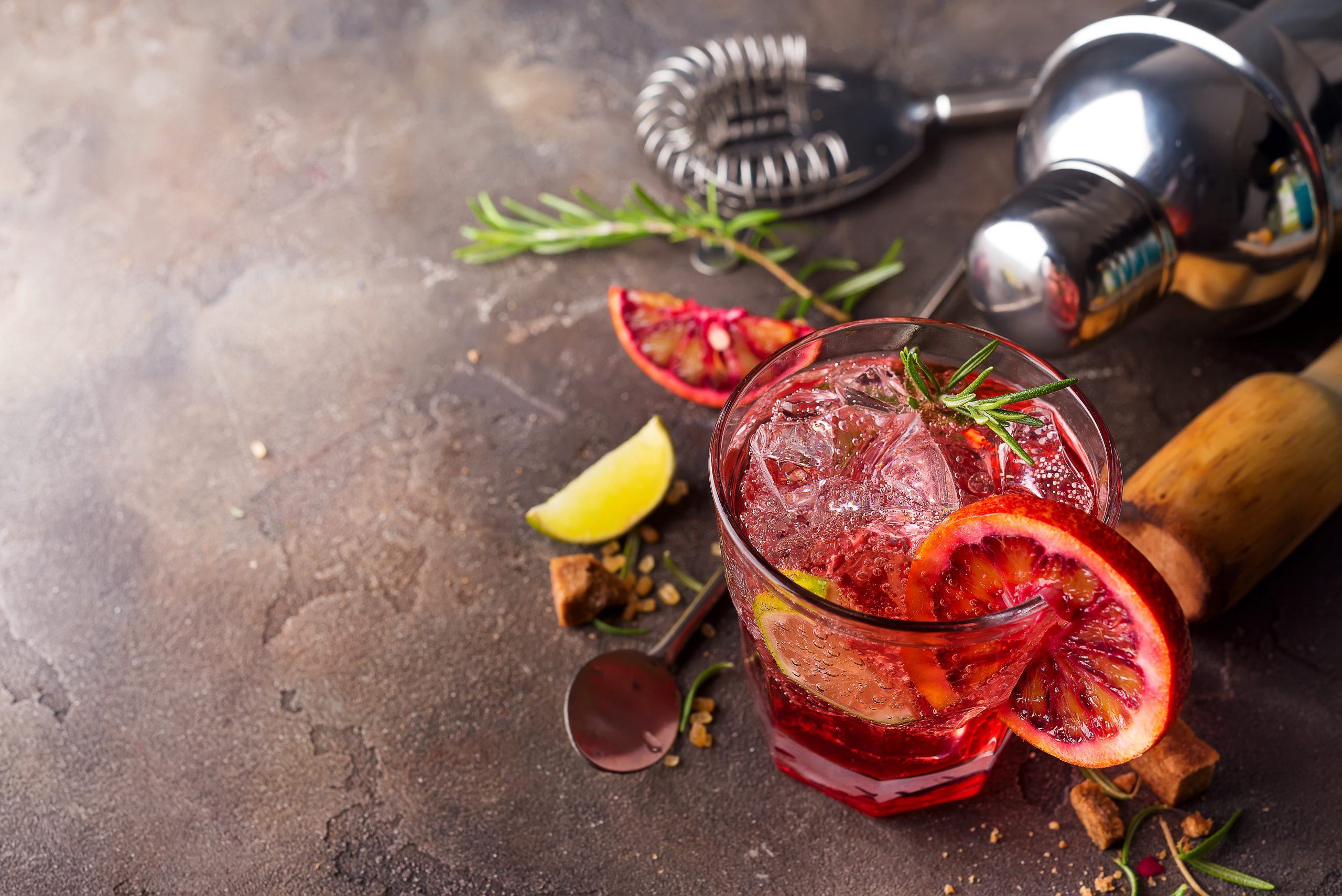 red Fresh colorful exotic alcoholic cocktail with orange and ice on a stone background. Red colorful Mojito
